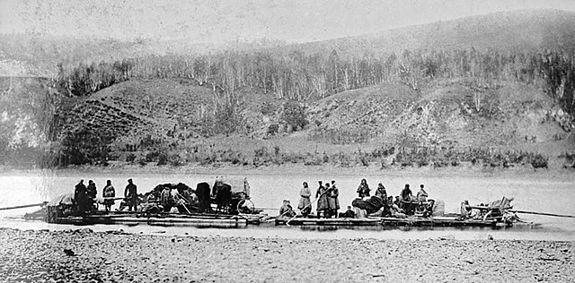 A back and white photo of a group of settlers riding a wooden raft down the Amur River.