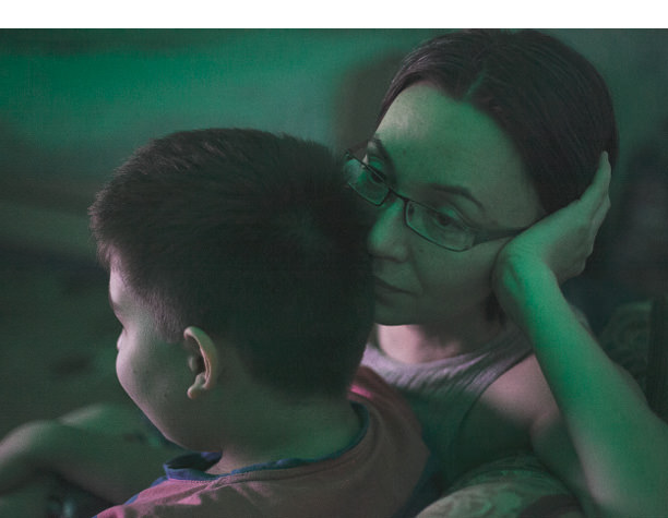 Anya and her son watch television at the end of the day.