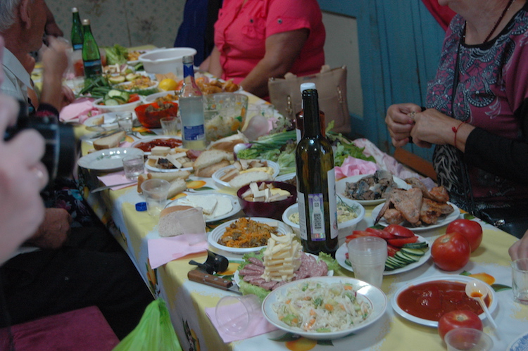 A table full of Russian delicacies, like vodka, cheese, meats, and salads.