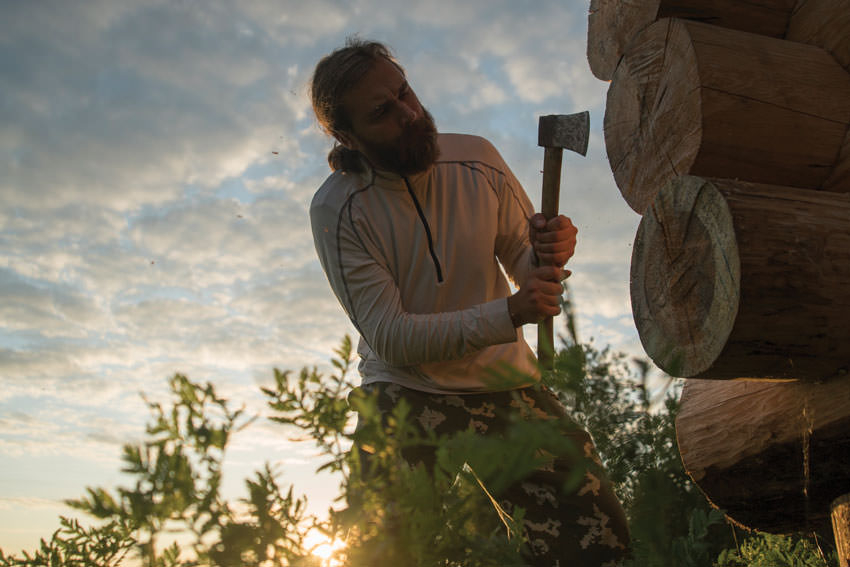 Man using axe to trim log.