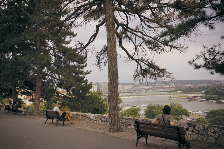 Man sitting on bench looking out over city.