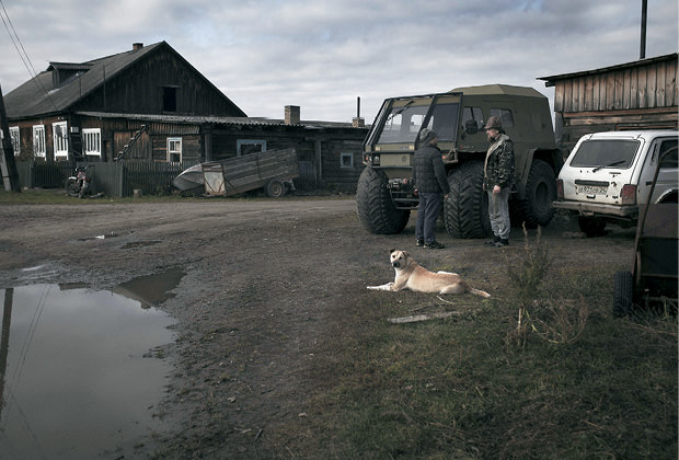 Men standing around a truck in a village.