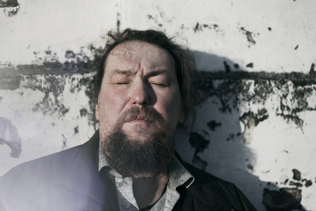 Man leaning back against a wall with eyes closed.