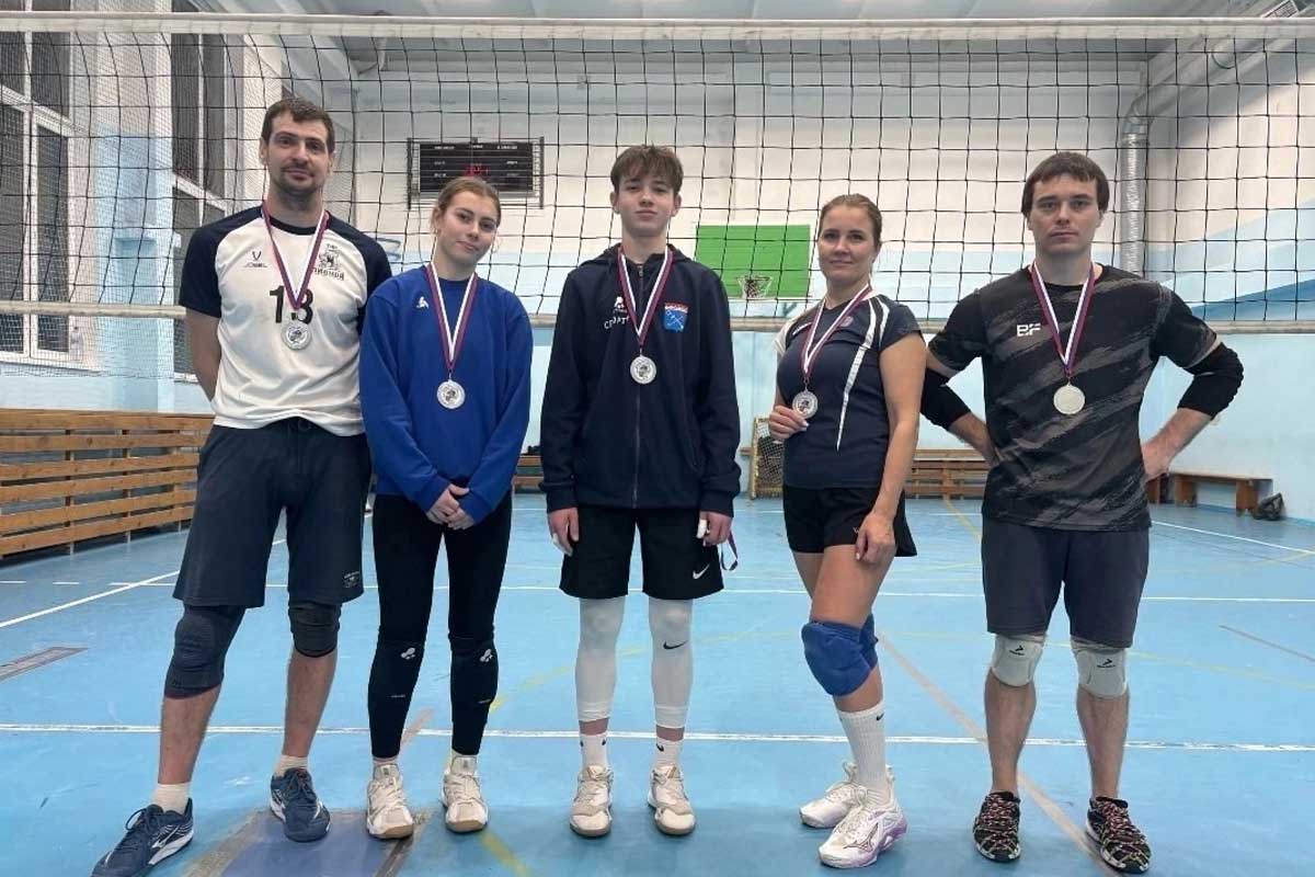 Boys and coach in front of volleyball net.