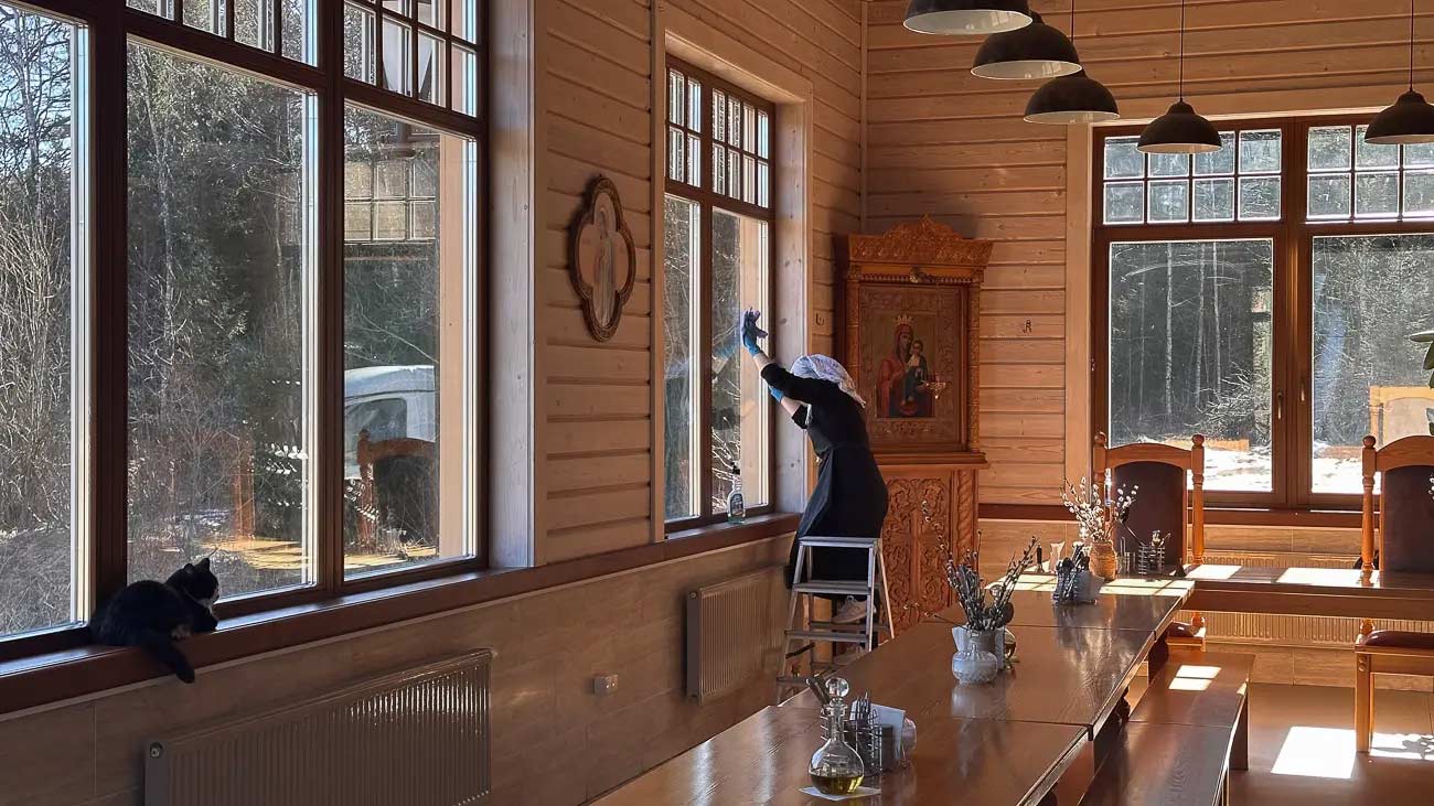 Woman cleaning window in a monastery.