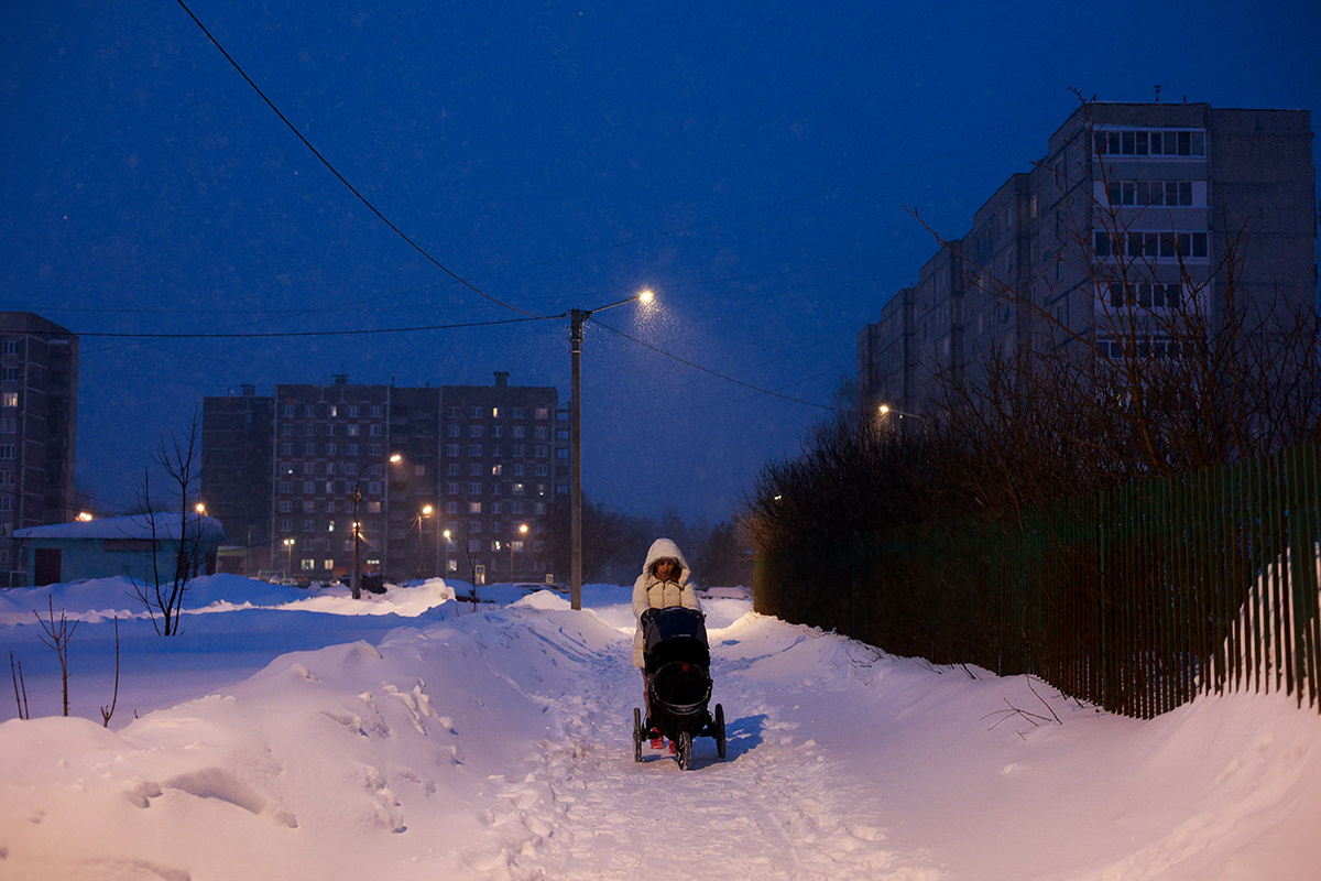 Woman walking stroller outside in winter.